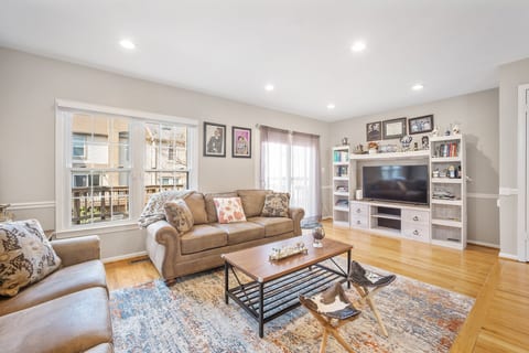 Bright living room with comfy sofas, big TV, and hardwood floors