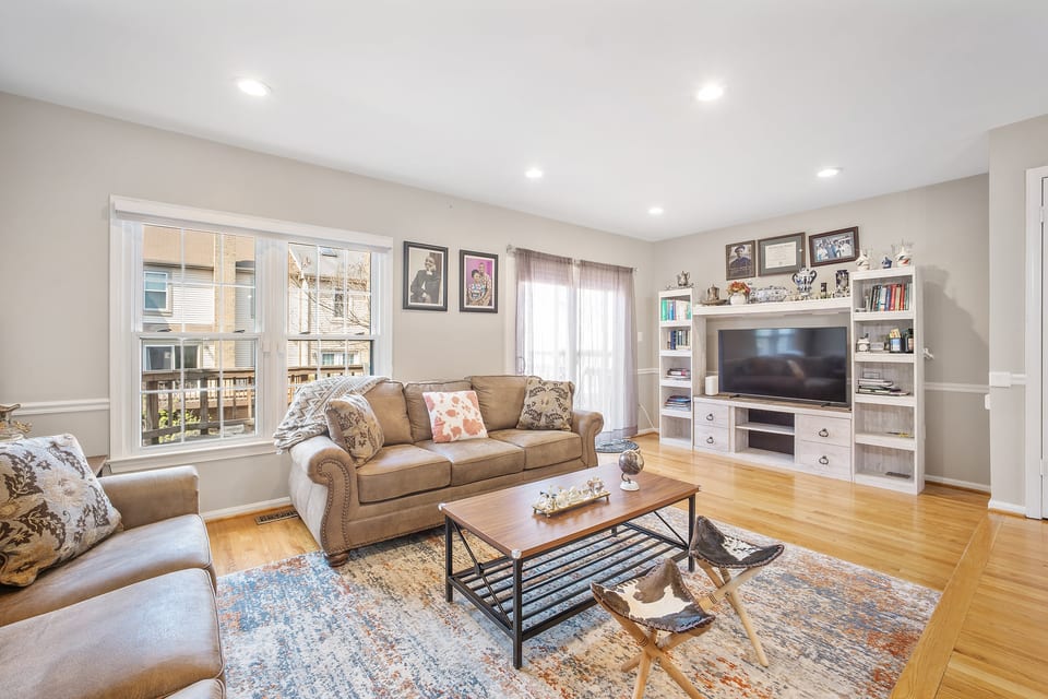 Bright living room with comfy sofas, big TV, and hardwood floors