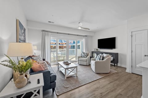 Primary living space with 3-seat couch, 2 swivel chairs, TV, and sliding glass doors to the private patio