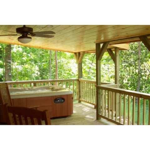 The covered porch features rockers and a hot tub, as well as a dining table and chairs..