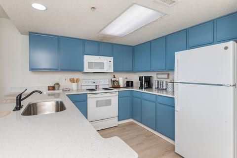Bright U-shaped kitchen with blue cabinets, quartz tops and coffee bar