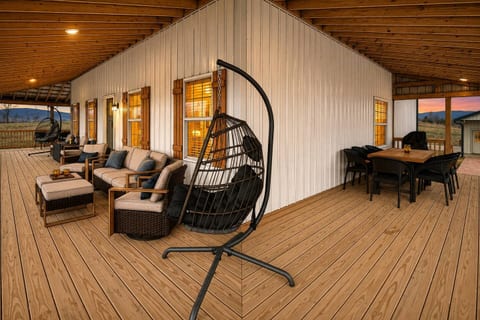Expansive covered outdoor living space featuring deep-seat sectional lounge chairs, egg swings, and outdoor dining.