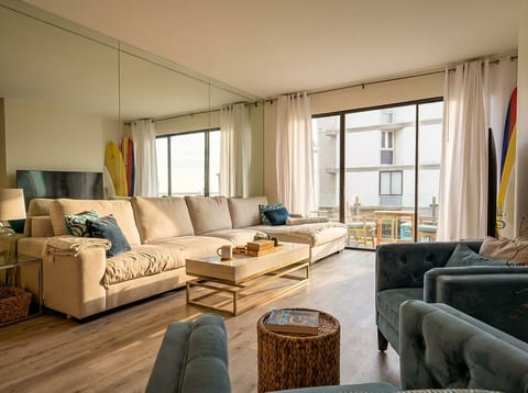Sunny coastal lounge with balcony, plush seating, and beachy vibes