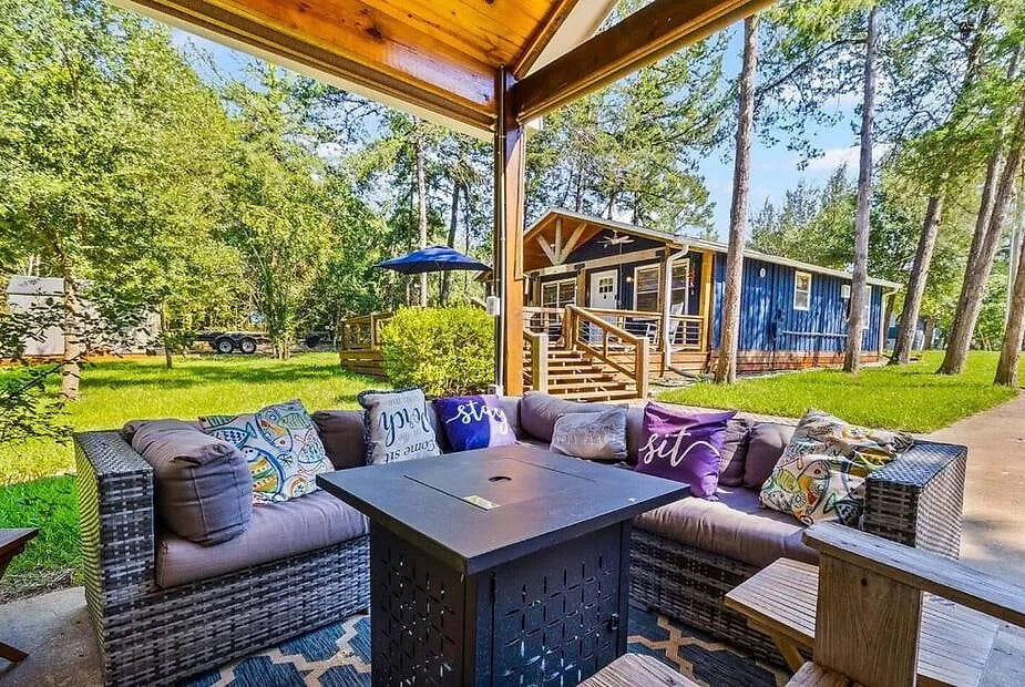 Wooded retreat: cushioned lounge + fire pit by a blue cabin deck