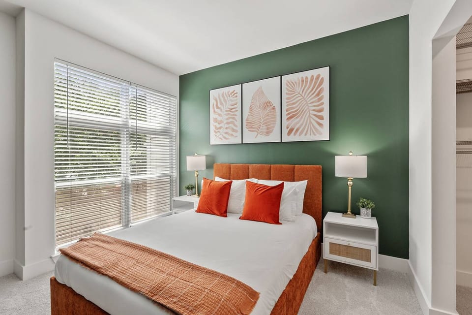 Serene bedroom with queen bed, bold accent wall, and abundant natural light