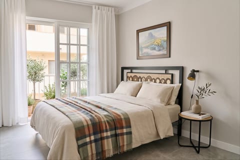 Bright, serene bedroom with balcony access and cozy, stylish touches.
