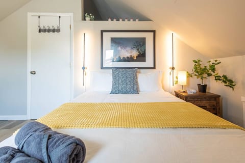 Inviting queen bedroom with symmetrical lighting, cozy textures, and thoughtful details—bright, calming, and perfectly set up for a restful night’s sleep.