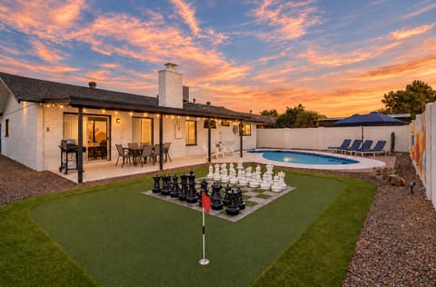 Resort-style backyard with pool, patio dining, and fun putting green