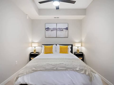 Cozy bedroom with a king-size bed, soft lighting, modern decor, and ceiling fan.