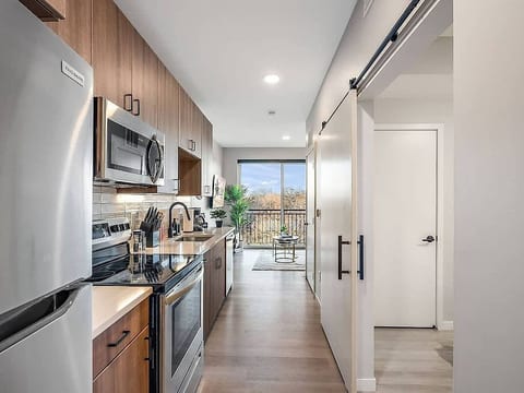 Modern kitchen with stainless steel appliances, sleek finishes, and balcony views.