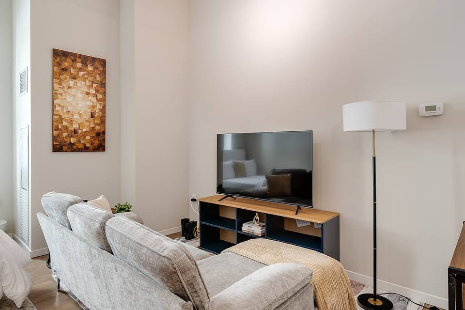 Relax in this cozy living space with a plush sofa, smart TV, and modern decor.