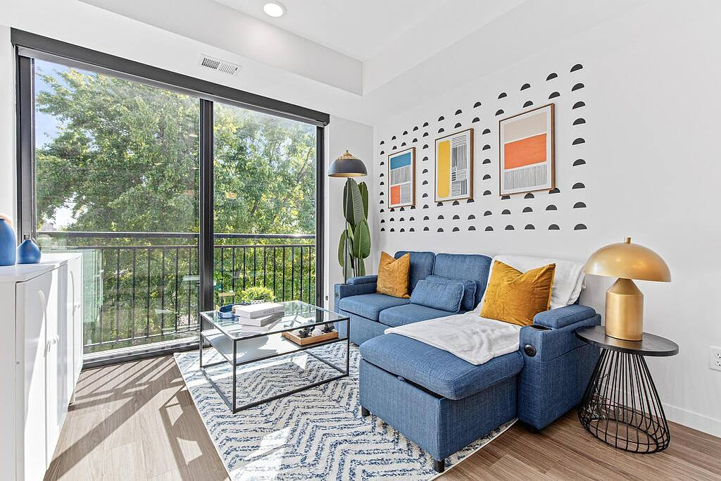 Right, modern apartment with cozy blue sofa, balcony views, & chic decor touches.