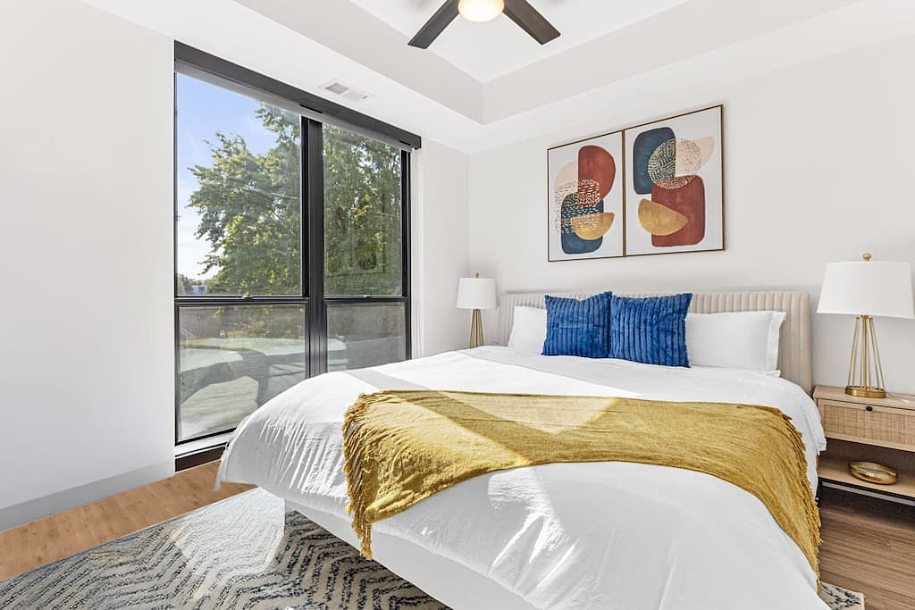 Relax in a serene bedroom with a plush king bed, natural light, and modern touches.