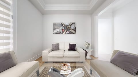 This living room features a plush sofa and armchairs with ample throw pillows, a coffee table with books for your enjoyment, and a decorative vase with flowers