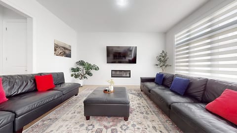 This modern living room offers a comfortable and stylish retreat for your stay. Relax on the two large leather sectional sofas, complete with red and blue accent pillows, perfect for unwinding after a day of exploring.