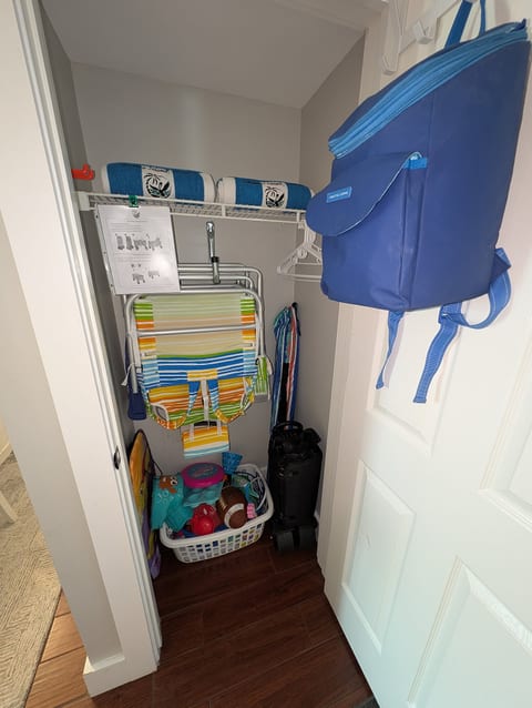 Beach-ready closet with beach wagon, chairs, towels, toys, umbrella, and cooler.