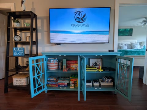 Family-friendly media hub with board games, books, smart TV, Atari game console, DVD, and coastal decor.