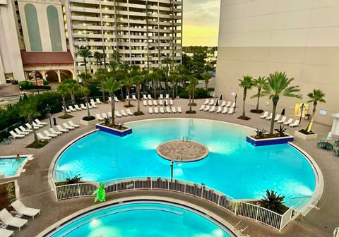 Resort-style lagoon pool surrounded by palm trees, loungers, and relaxing tropical vibes.