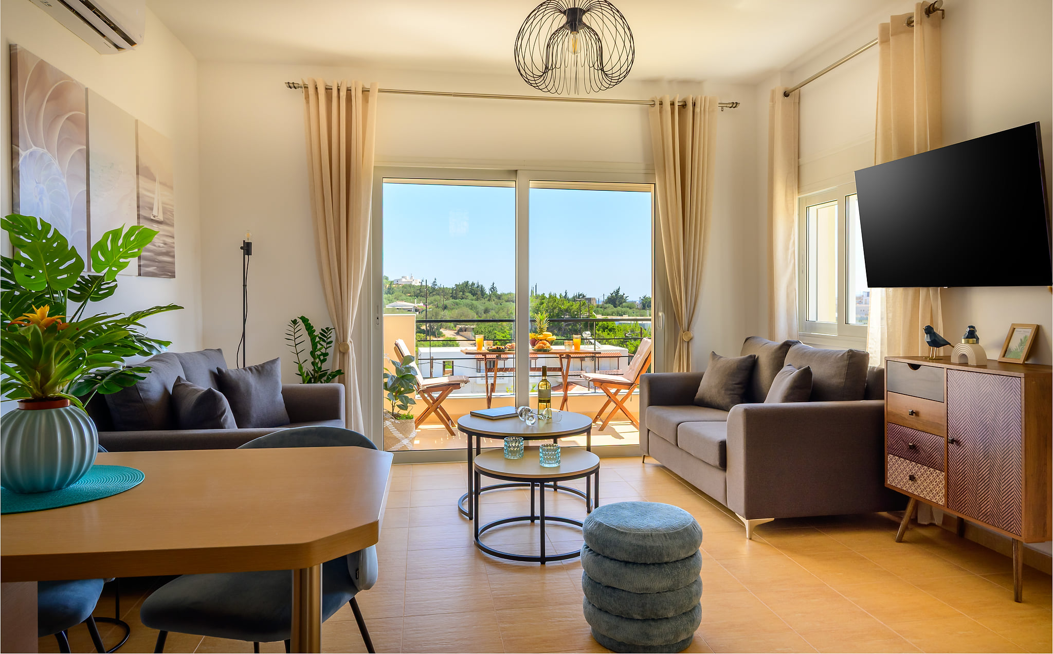 Bright living room with balcony dining, lush views, AC and smart TV.