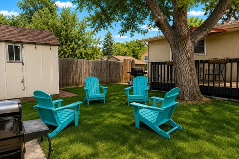 Private backyard with shaded lawn, grill, and colorful Adirondack seating