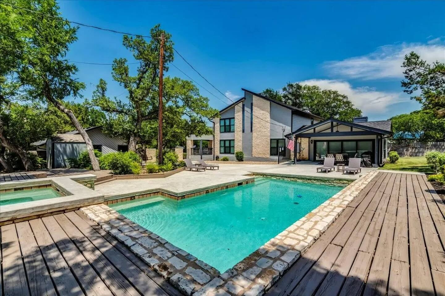 Expansive pool and spa area with wide wood decking, Hill Country views, and modern lounge seating—a private, resort-style space for relaxing and entertaining.

