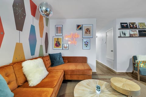Retro living room with a velvet sectional under a disco ball. Pick an album off the wall and let the good vibes roll.