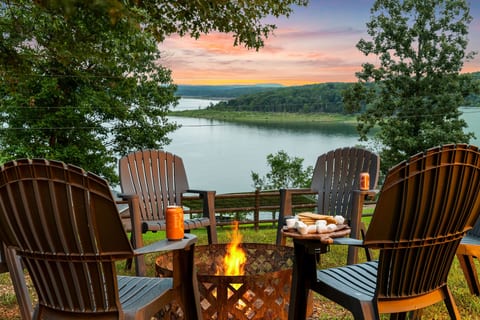 Pull an Adirondack up to the fire and load the s'mores board as the sky goes pink behind the lake — this is the fire pit at golden hour. Nothing beats it.