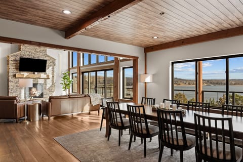 Spacious open-concept living and dining area with vaulted wood ceilings, large windows, and sweeping scenic views—perfect for gathering, dining, and relaxing in comfort.