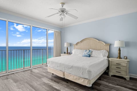 Gulf-front master bedroom with king bed and floor-to-ceiling balcony views of emerald waters.