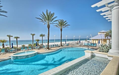 Resort-style pool surrounded by palm trees and direct access to the white sand beach.