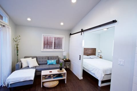View of living room and bedroom with large sliding barn door for privacy.