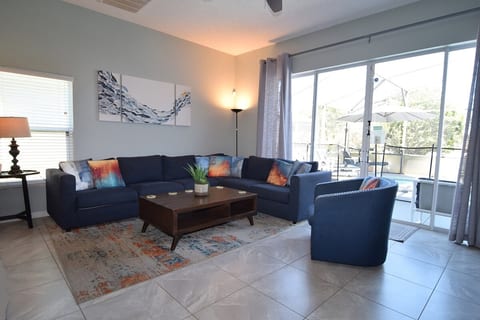 Stylish open-plan living space with Smart TV, ceiling fan and sliding doors to the pool deck