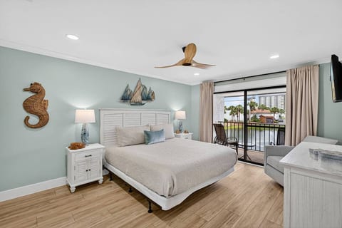 Relax in the spacious primary bedroom featuring a king size bed, private balcony access, and peaceful lake views.