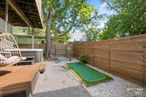Relaxing backyard retreat with a hanging chair, hot tub, and soft evening lighting. A peaceful spot to sip, soak, and settle in.