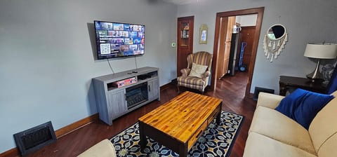 Relax in this cozy living room featuring a smart TV with Netflix, comfy sofa and chairs, and a stylish coffee table. The warm wood accents, soft lighting, and inviting decor make it perfect for movie nights, reading, or simply unwinding together.