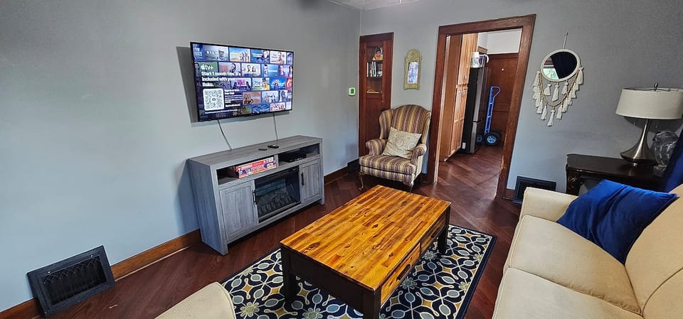 Relax in this cozy living room featuring a smart TV with Netflix, comfy sofa and chairs, and a stylish coffee table. The warm wood accents, soft lighting, and inviting decor make it perfect for movie nights, reading, or simply unwinding together.