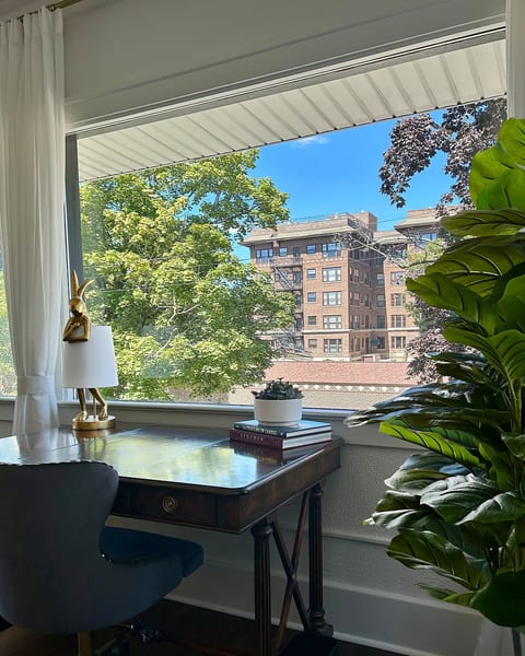 Vintage desk and comfortable chair with natural light and downtown views, perfect for remote work or study.