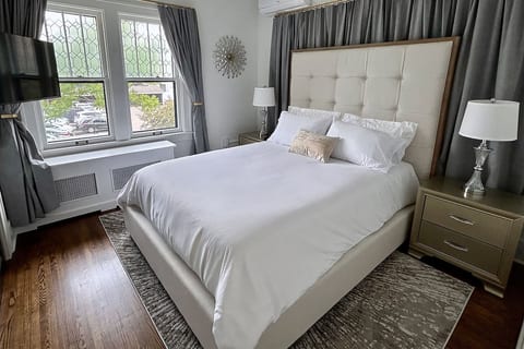 Tranquil bedroom with a queen bed, Roku TV, blackout curtains, and a large closet with shelves, hangers, and luggage racks.