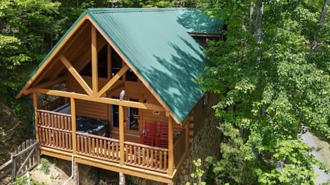 Cozy wooded cabin with covered deck, rocking chairs, and hot tub