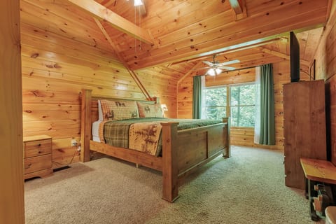 Cozy wood-lined cabin bedroom with forest views and vaulted ceilings