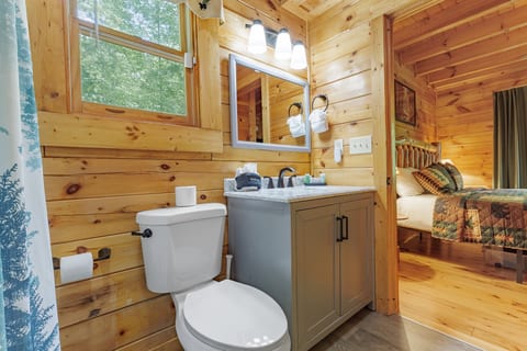 Bright cabin bathroom with wooded views and cozy bedroom access