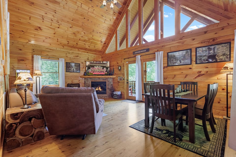 Cozy log cabin great room with fireplace, vaulted ceilings, and deck access