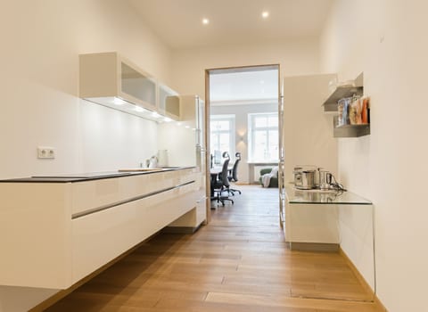 Bright, modern galley kitchen with glossy cabinets and wood floors