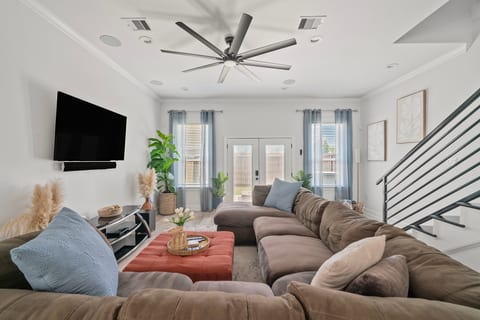 Bright open living room with oversized sectional, TV, and French doors