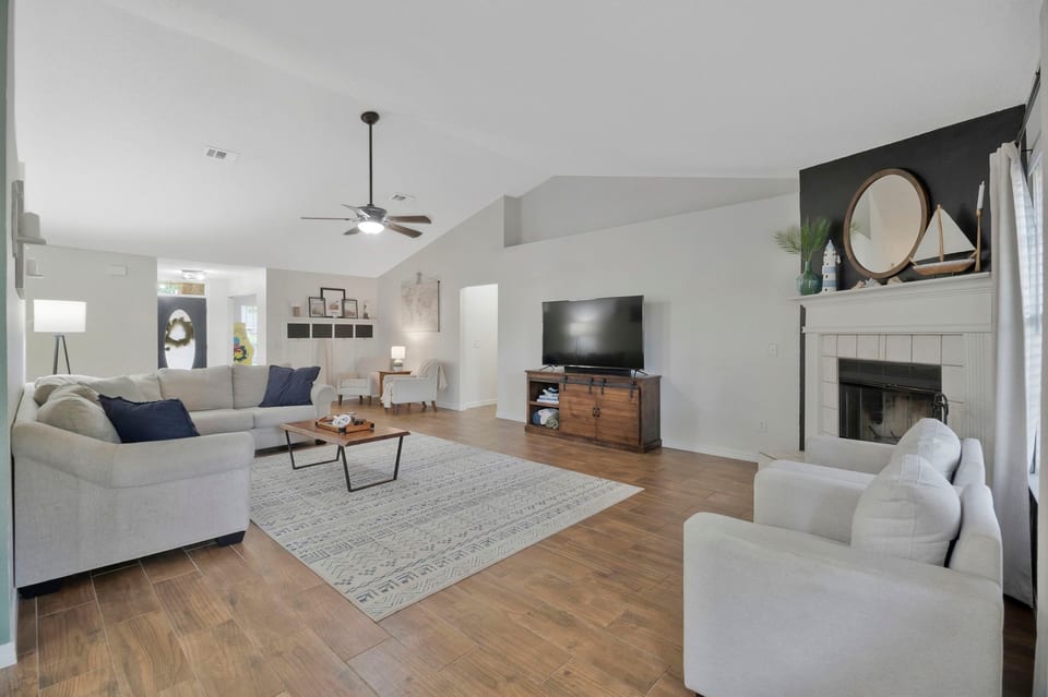 Bright open living room with fireplace, vaulted ceilings, and cozy seating