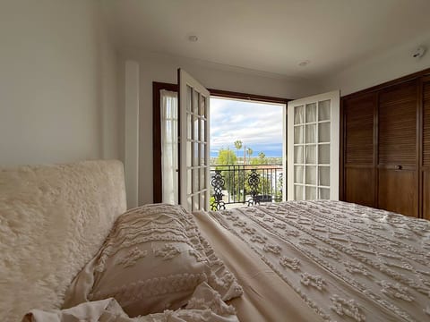 Wake up to stunning valley views from this cozy California king bed, wrapped in luxe textured bedding. The double French doors open wide to a private balcony, letting in natural light, fresh air, and serene morning skies. A true peaceful escape.