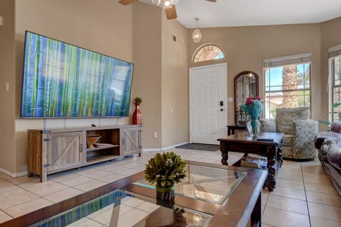 Sunny living room with large smart TV, vaulted ceiling & tile floors