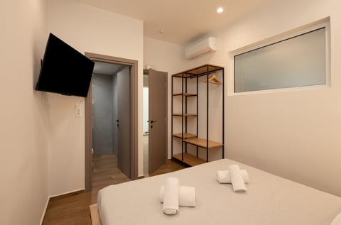 Modern bedroom with TV, A/C, and open wardrobe storage