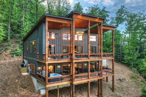 Two-level cabin with wraparound decks, warm wood accents, and hot tub nestled in the woods