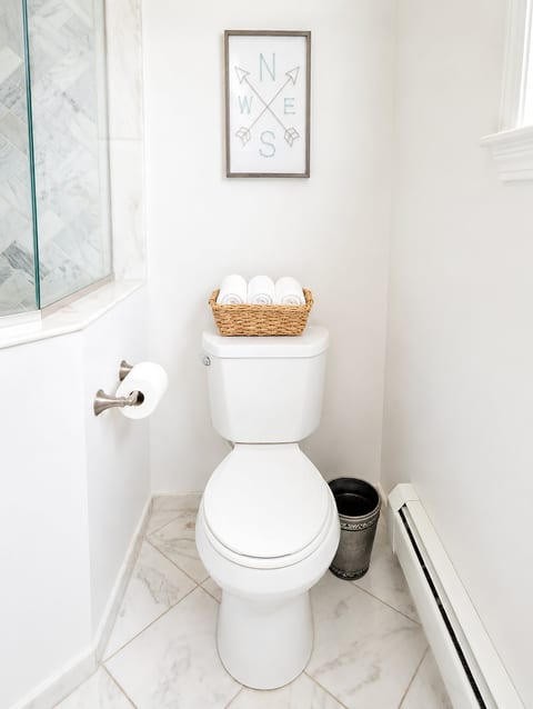 Bright, spotless bathroom with marble-look tile and fresh guest touches